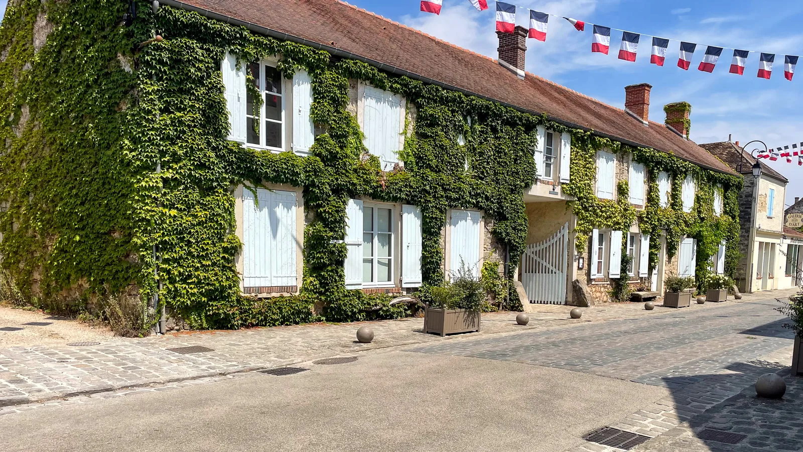 Façade en pierre de l'Auberge Ganne, couverte de lierre, sur la Grande Rue de Barbizon.