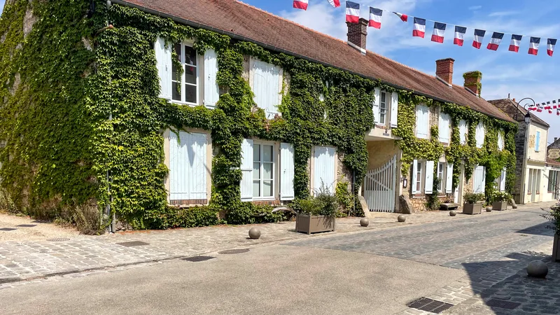 Façade en pierre de l'Auberge Ganne, couverte de lierre, sur la Grande Rue de Barbizon.